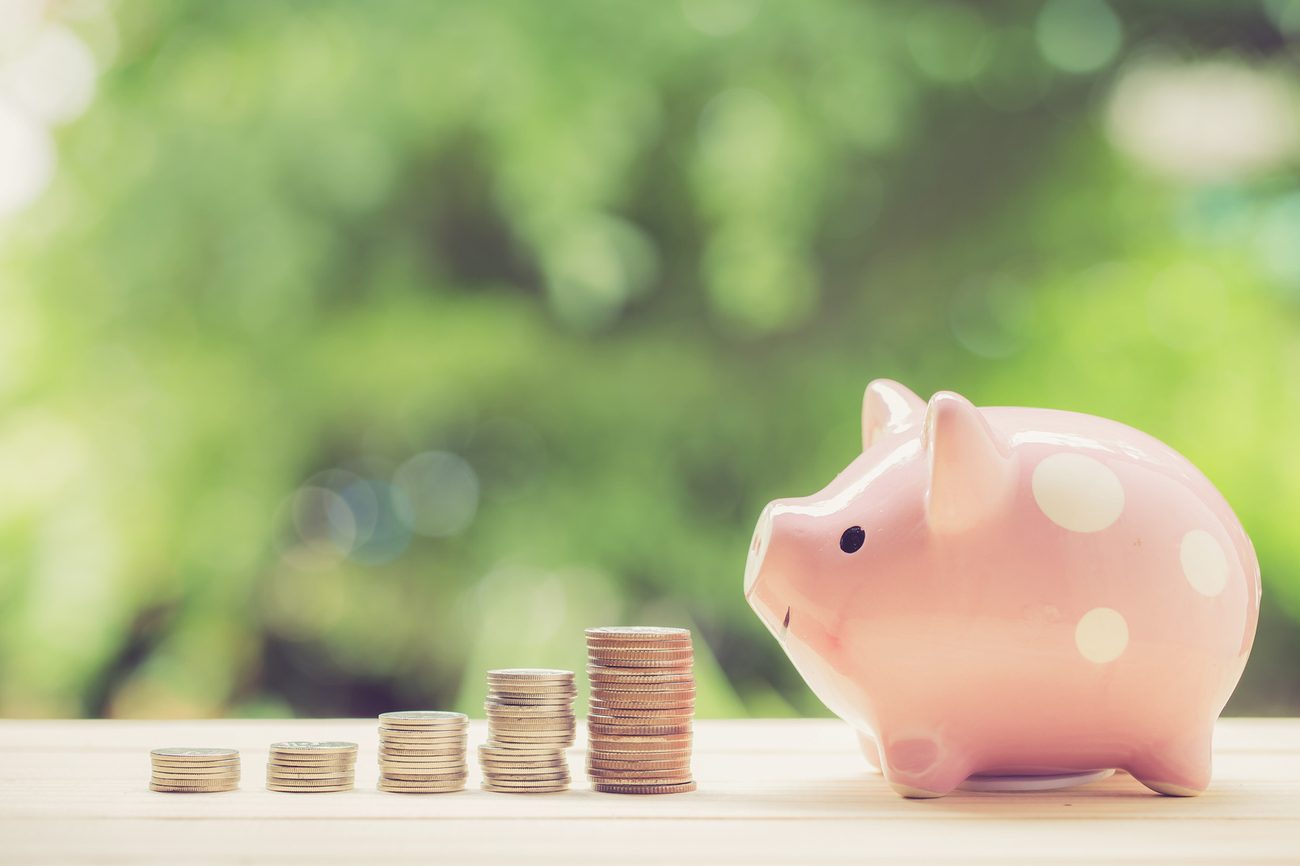 Piggy bank beside growing stacks of coins